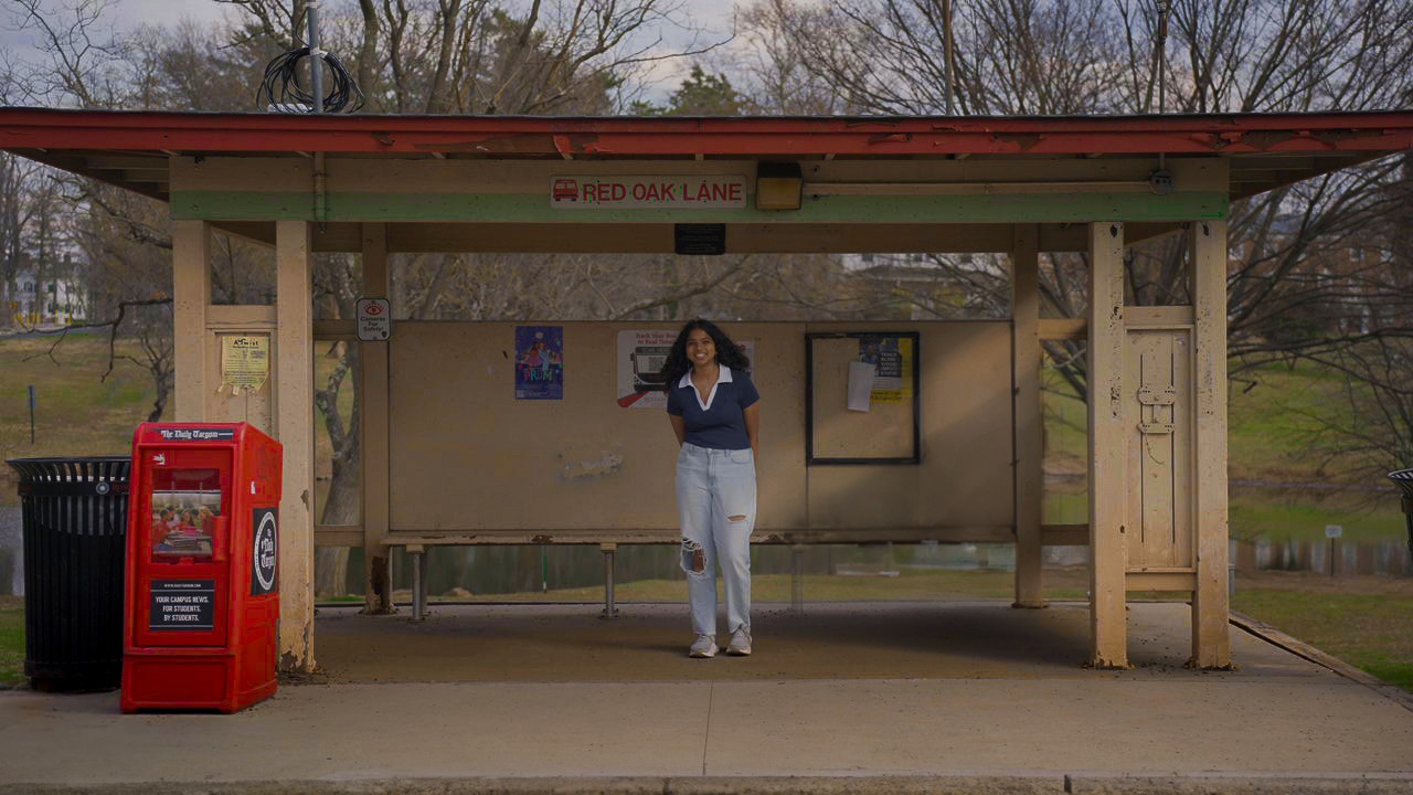 Main character is smiling at camera at the bus stop
