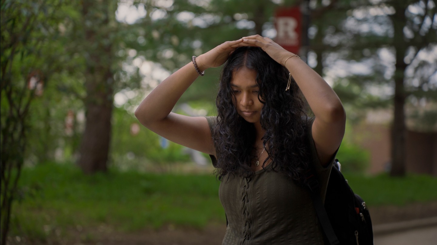 Main character is drenched and covering her head from rain